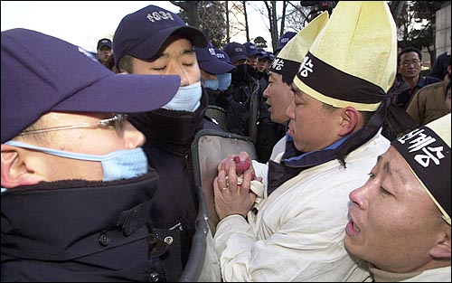 상복을 입은 고 배달호씨의 동료 해고자들과 상공회의소를 경비하는 경찰들이 몸싸움을 벌이고 있다. 